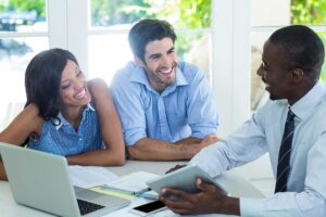 A smiling family reviews home inspection documents with an agent at a kitchen table.