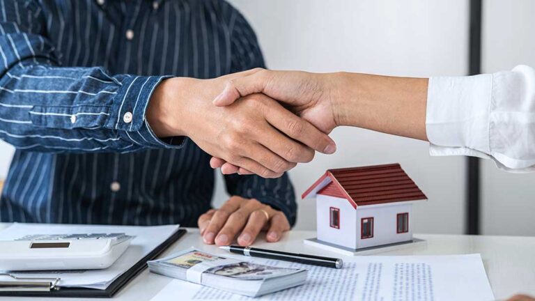 Buyer and real estate agent reviewing property documents at a kitchen table.